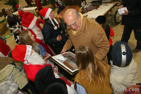 Les enfants offrent un cadeau à M. Charles Burrus lors du spectacle de Noël 2004